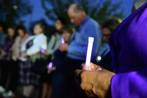 Atendees of The Center for Family Justice's Domestic Violence Awareness Vigil hold a moment of silence as they hold purple glow sticks during the vigil at the Bridgeport Police Department memorial in Bridgeport, Conn., on Tuesday Oct. 1, 2019.