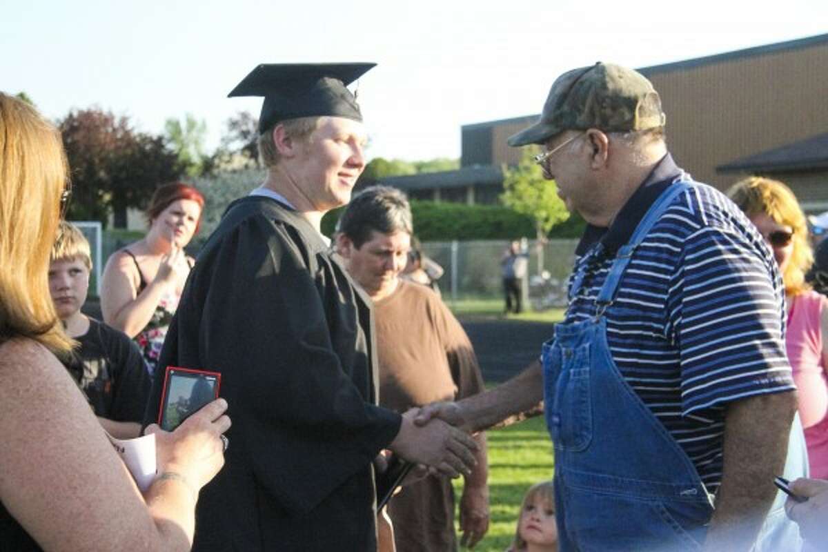 FAMILY: Kalub Robinson receives a hand shake from his grandfather after graduation. (Herald Review photo/Emily Grove-Davis)