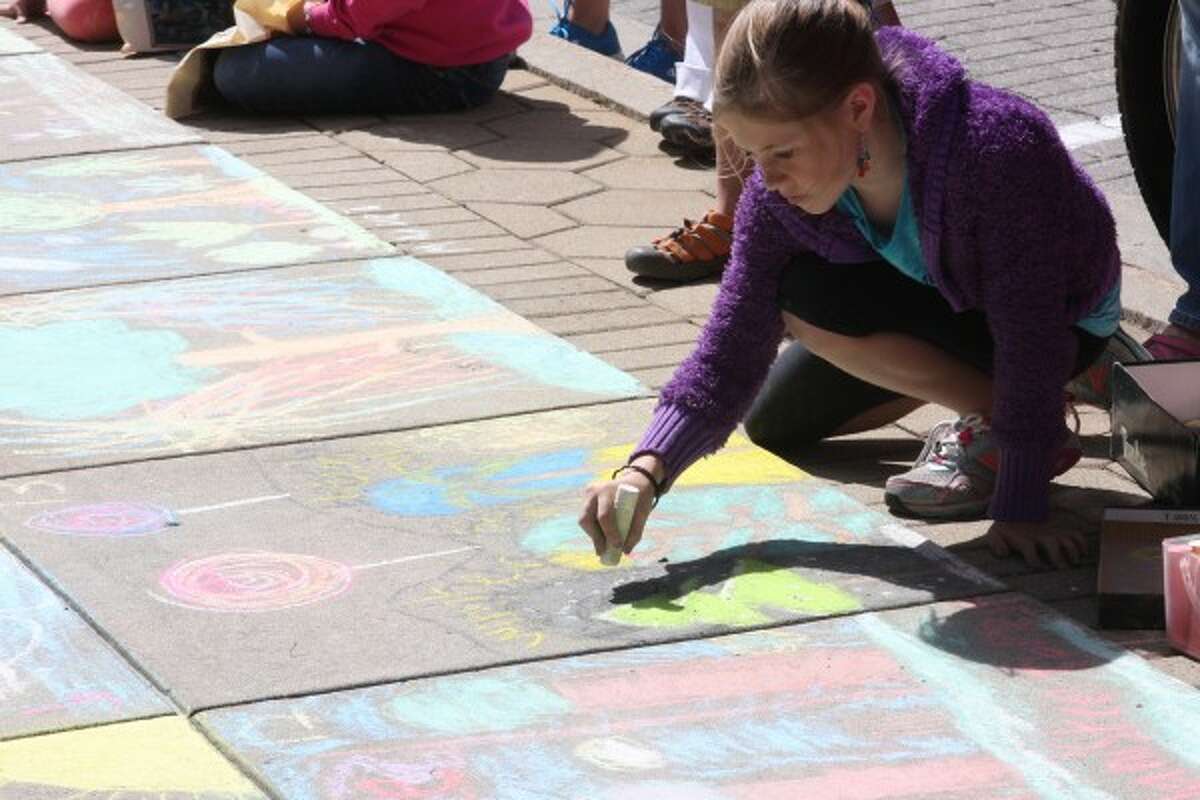 Olivia Schubert, 10, of Rockford, works diligently on her tree-themed entry into the Manistee National Forest Chalk Art Contest on Wednesday. (Justine McGuire/News Advocate)