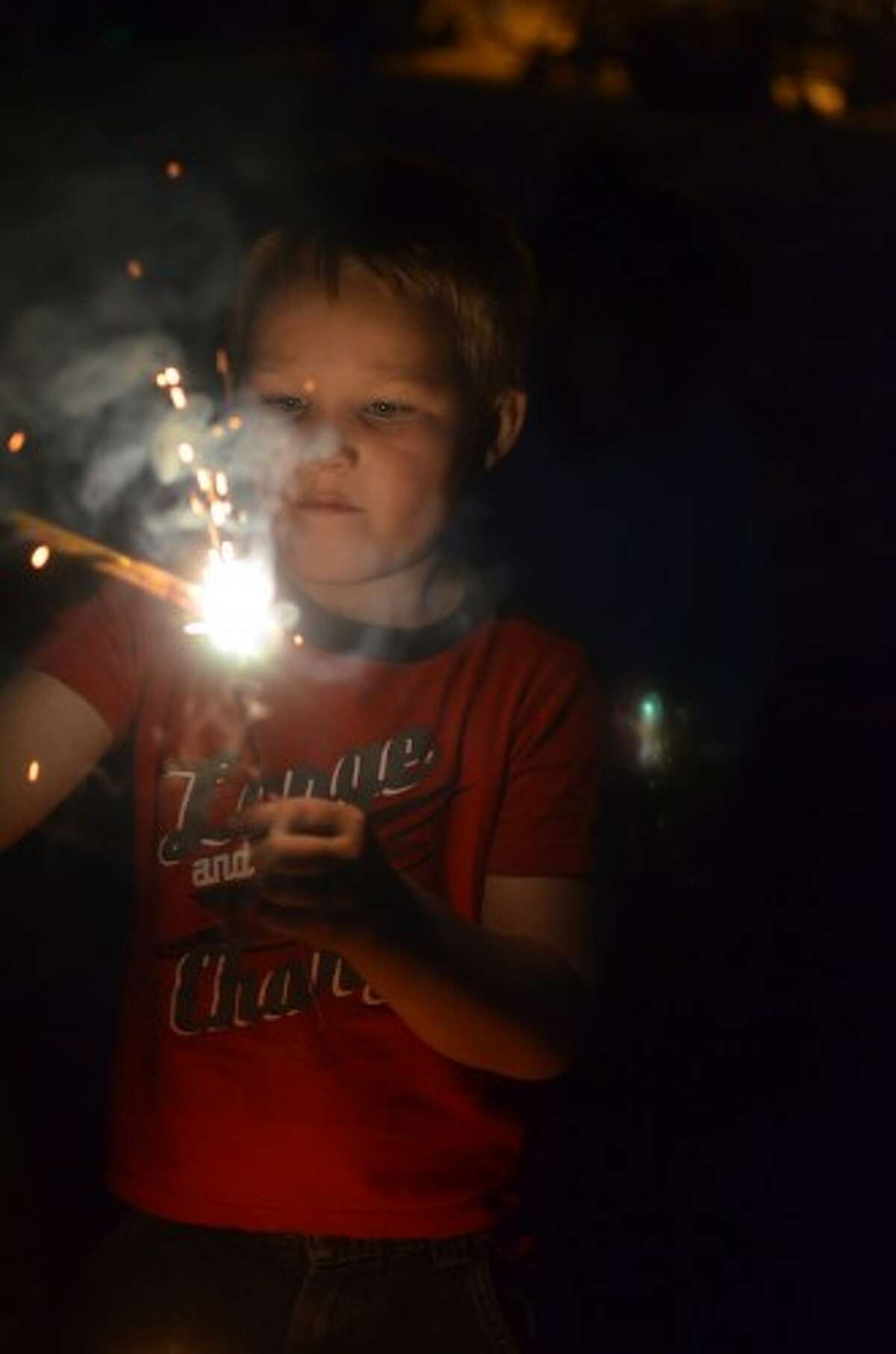 Joe Pyler II, 5, of Manistee, lights a sparkler at First Street Beach before the fireworks Friday night. (David Navadeh/News Advocate)