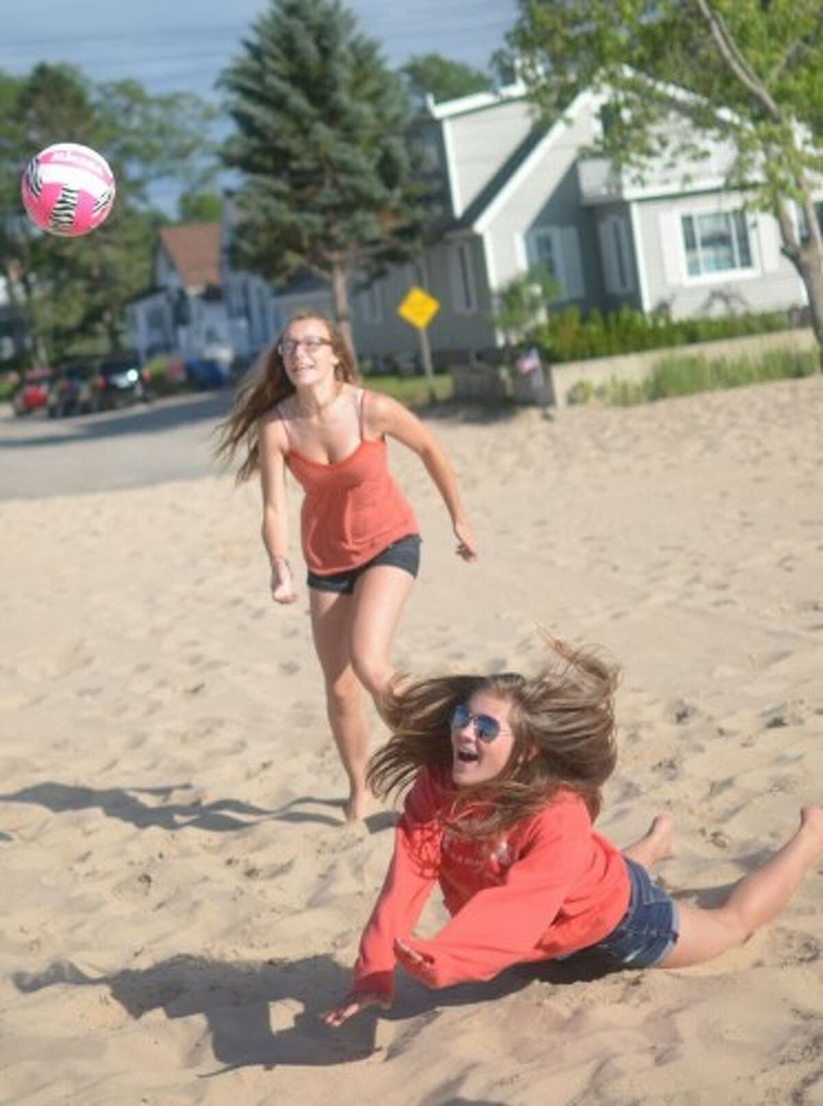 Devon Edmondson, 15, of Manistee, runs for the volleyball while Katie Sidor, 13, of Bear Lake, dives for it. (David Navadeh/News Advocate)