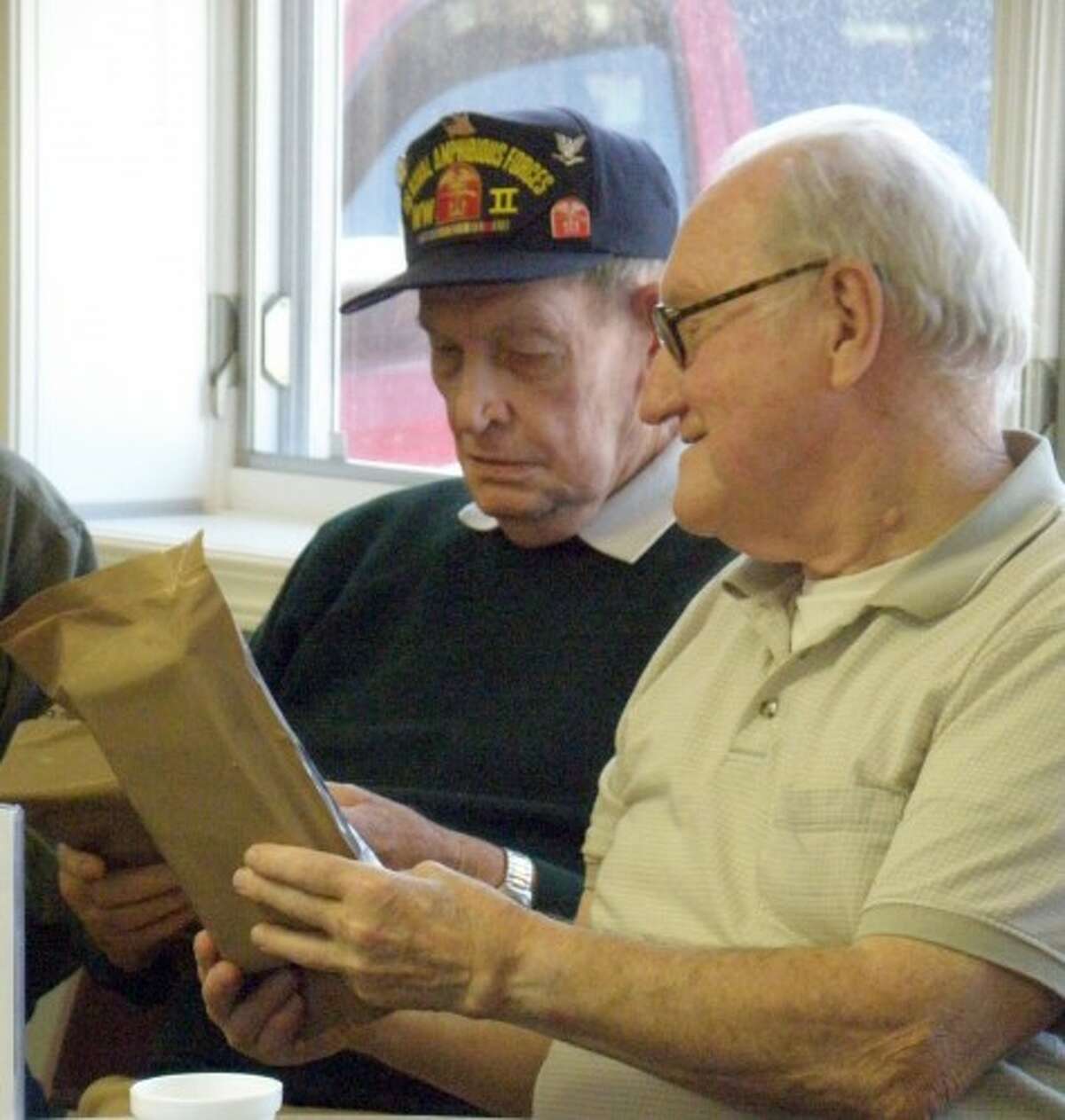 WWII veteran Darwin Anderson (left) and Korean War veteran Eugene Erlandson inspect the modern day MRE (meals ready to eat) on Wednesday during Veterans Exchange day at the Manistee Senior Center. (Jeanne Barber/Courtesy photo)