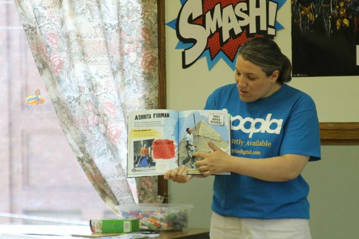 Andrea Cosier, youth services director at the Manistee County Library, reads from a book about world record holders during the Sports Heroes Challenge at the Manistee Library on Thursday. (Justine McGuire/News Advocate)