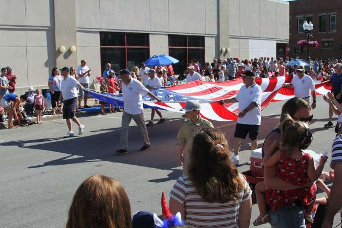 Parade goers carry the large American flag down River Street in Manistee. (Ashlyn Korienek/News Advocate)