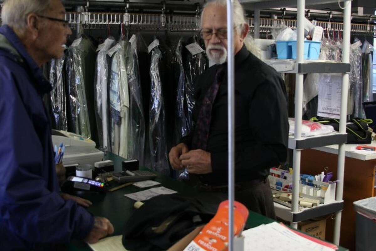 Harold Jacobs (left) drops of a pair of slacks in need of hemming Wednesday to Byron Joseph (right), owner of American Cleaners in Manistee. (Sean Bradley/News Advocate)