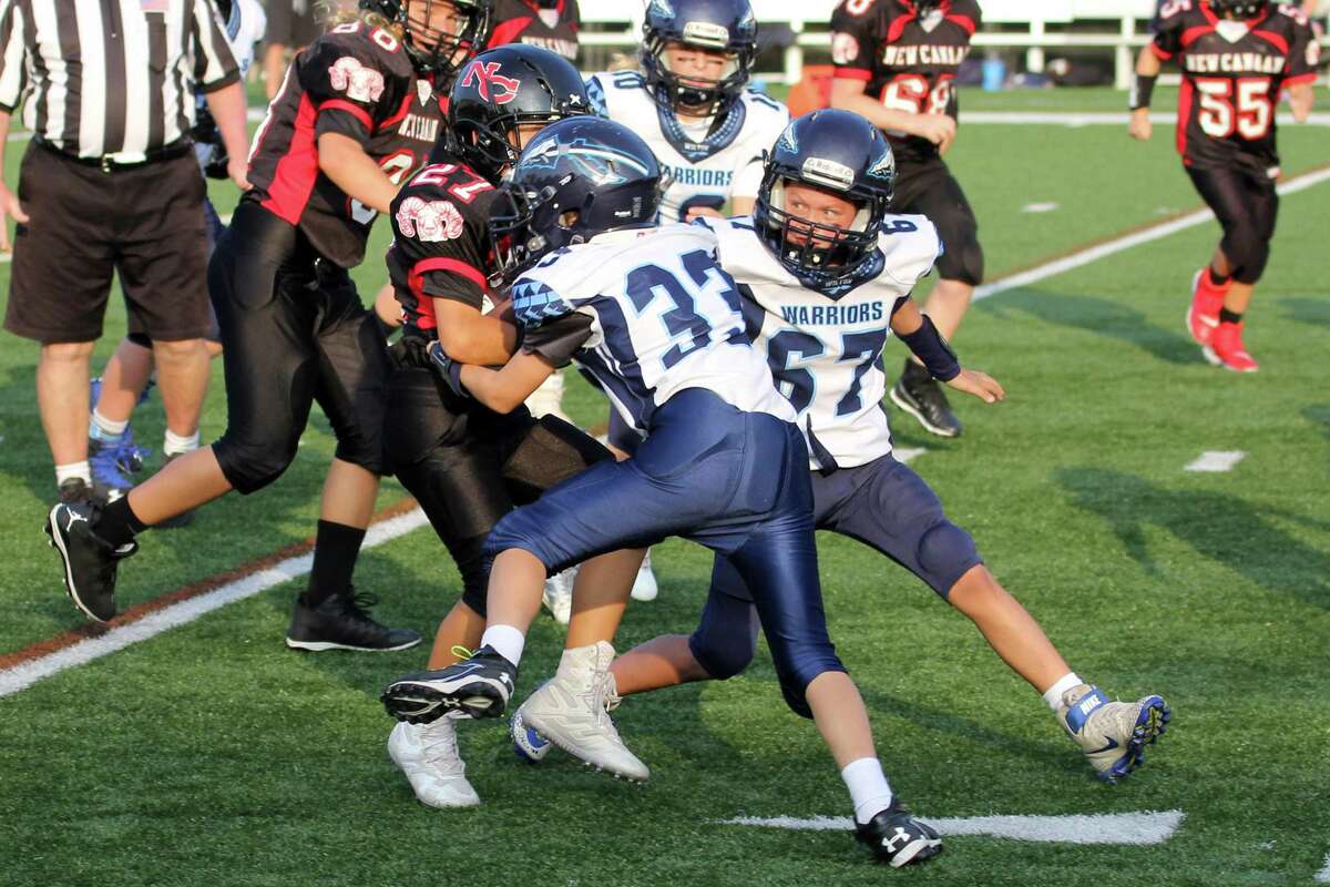 Wilton's Will Byrnes (#33) makes a tackle with help from teammates Evan Christianson (#67) and Emma Van Heyst (#10) during a 6th Grade youth football game.