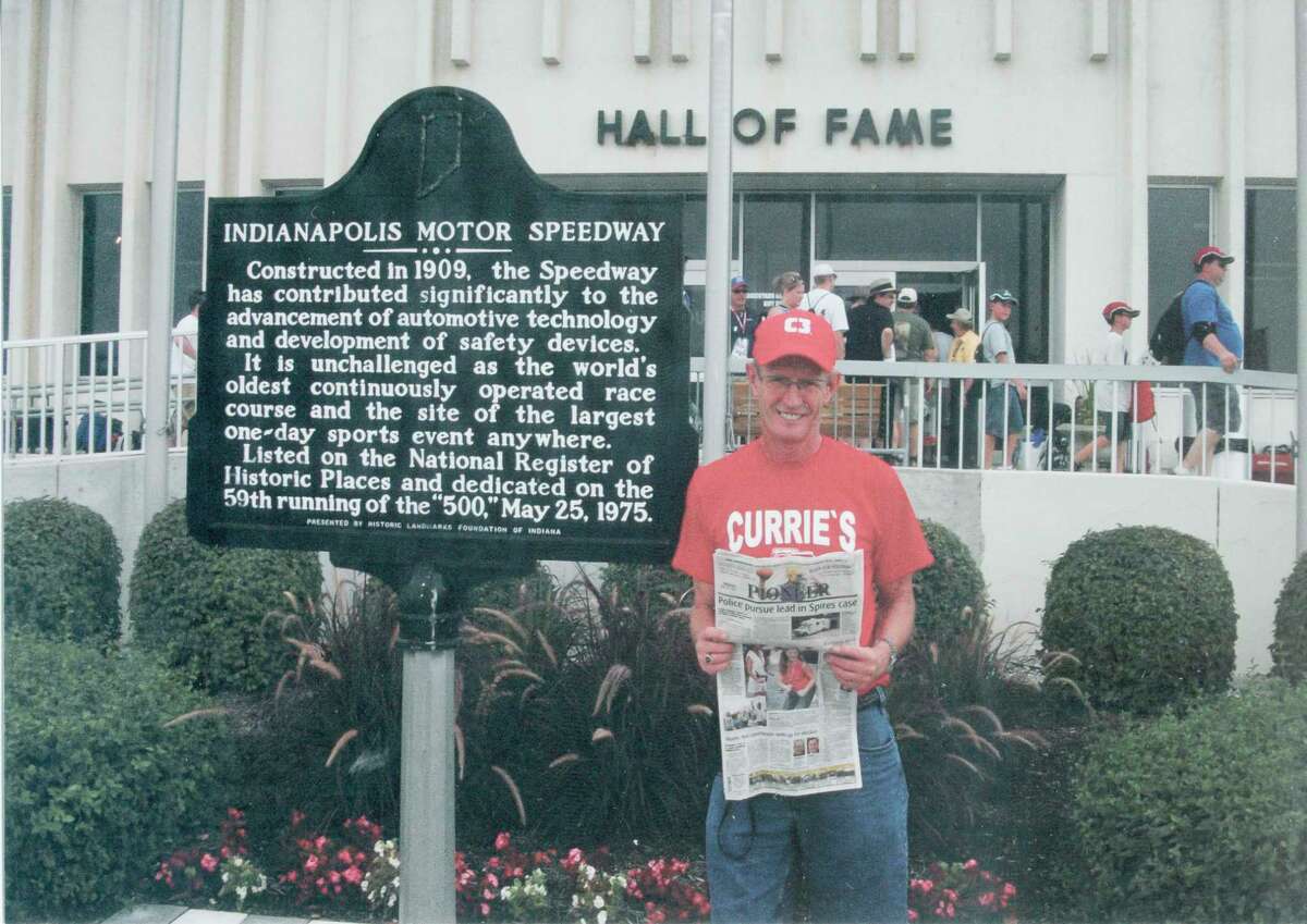 SPEED: Bruce Parker, of Big Rapids, was at the Indianapolis Motor Speedway on July 31 for the Brickyard 400 race. Here, he takes time to read the Pioneer. Behind him is the Indianapolis Motor Speedway Hall of Fame. (Courtesy photo)