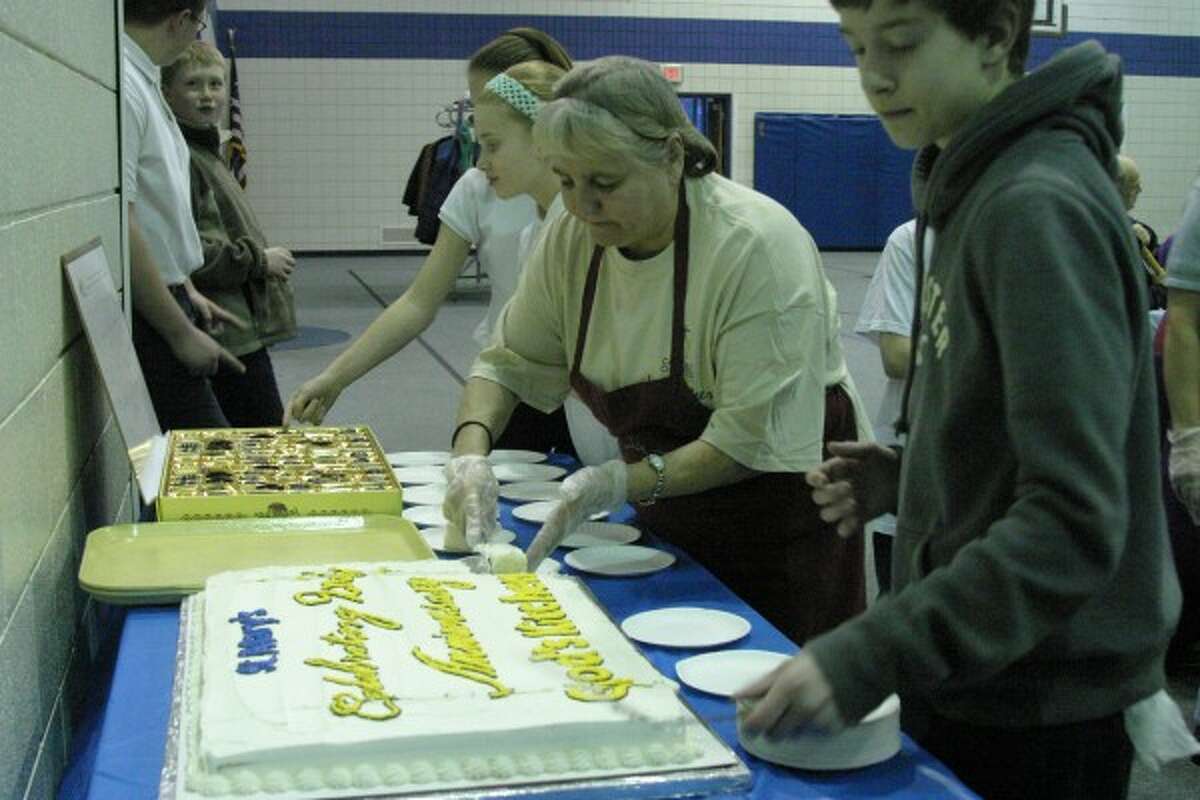 CAKE: Volunteers cut and serve slices of cake to attendees of the weekly God’s Kitchen meal on Tuesday. The Catholic ministry celebrated its second anniversary with a special prayer prior to the meal led by Father Lam Le.