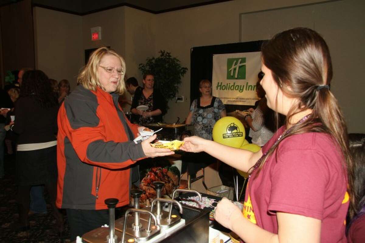 TASTE OF MECOSTA: Mary Ann Lenon, director of the Morton Township Library, gets a basket of chicken from the Buffalo Wild Wings table at the 2012 Taste of Mecosta on Fat Tuesday at the Holiday Inn in Big Rapids.