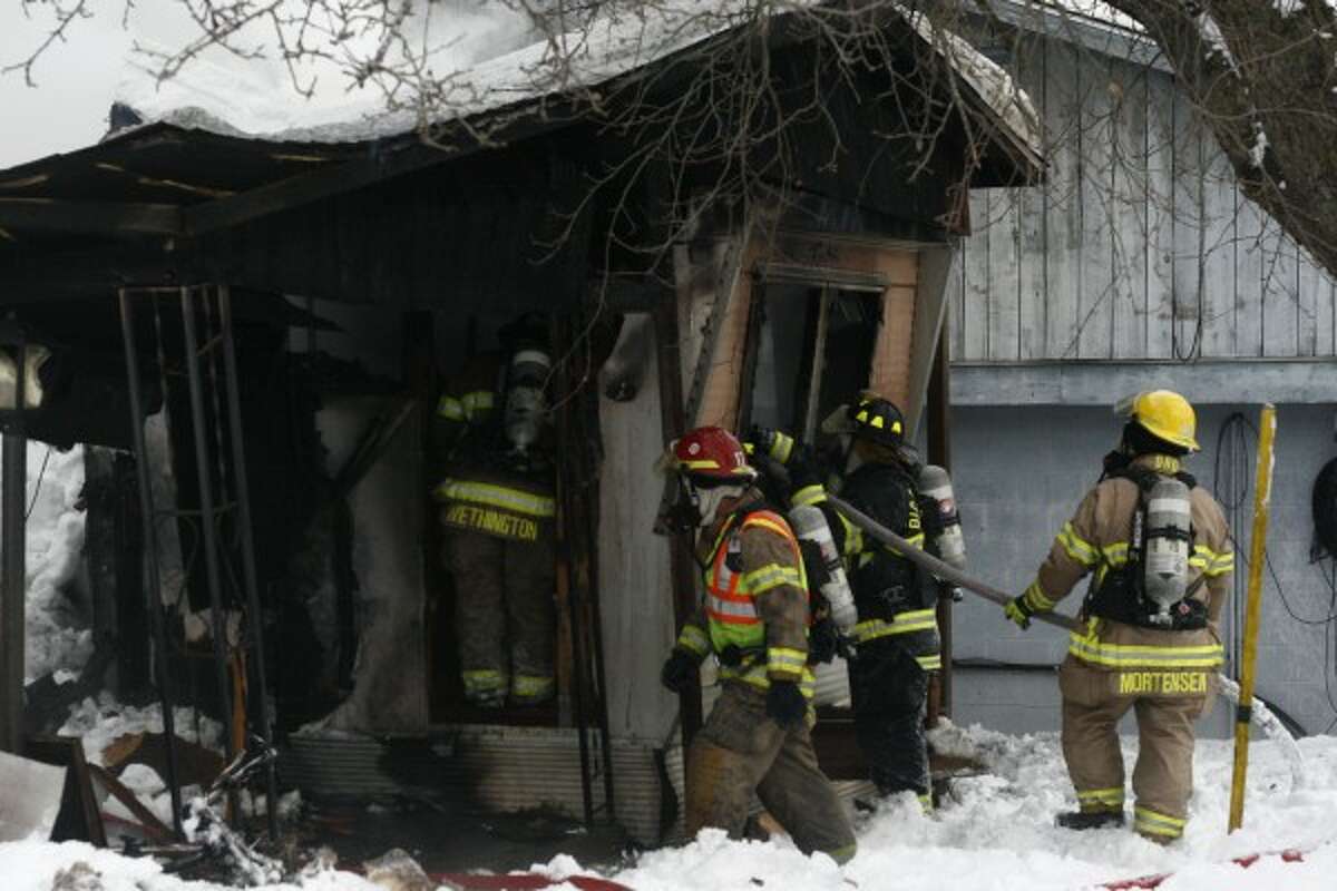 Firefighters attempt to gain entry to the area of the trailer where the roof collapsed. The tenant was found dead inside the home. (Pioneer photos/Whitney Gronski-Buffa)