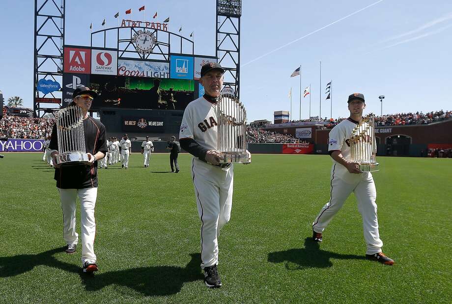 San Francisco Giants, from left,  pitcher Tim Lincecum, manager Bruce Bochy and catcher Buster Posey carry the Giants World Series trophies from the 2010, 2012 and 2014 seasons before a baseball game between the Giants and the Colorado Rockies in San Francisco, Monday, April 13, 2015. (AP Photo/Jeff Chiu, Pool) Photo: Jeff Chiu / Associated Press