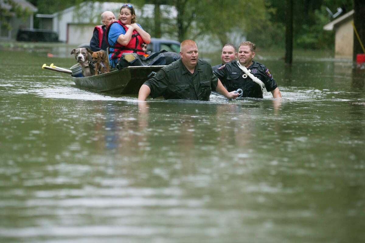 Splendora Police Lt. Troy Teller, left, Cpl. Jacob Rutherford and Mike Jones pull a boat carrying Anita McFadden and Fred Stewart from their flooded neighborhood inundated by rain from Tropical Depression Imelda on Thursday, Sept. 19, 2019, in Spendora, Texas. (Brett Coomer/Houston Chronicle via AP)