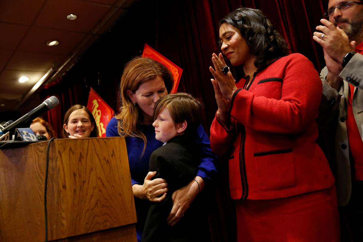 Suzy Loftus (third from left), interim district attorney, kisses her daughter Grace Loftus (third from right) during a press conference at Far East Cafe after Mayor London Breed (second from right) announced the appointment of Suzy Loftus as interim district attorney on Friday October 4, 2019 in San Francisco, Calif. Loftus’ other two daughters Maureen Loftus (left), 14 and Vivienne Loftus (second from left), 12 applaud as they stand with their mother.