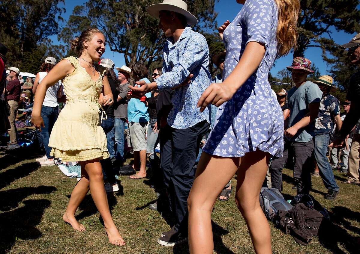 A young woman who declined to be identified enjoys the music, sunshine and vibe barefoot in the grass while attending the opening afternoon of Hardly Strictly Bluegrass music festival at Hellman Hollow in Golden Gate Park, San Francisco, Calif. on Friday, October 4, 2019