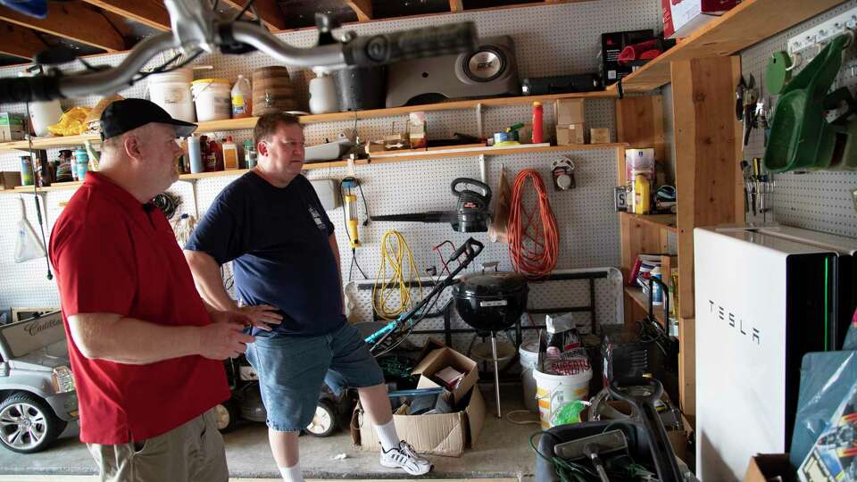 Erik Sweet, and Jon Sweet take a look at a Tesla powerwall battery during a visit to the home of Jose Flores on Saturday, Oct. 5, 2019, in Clear Creek.