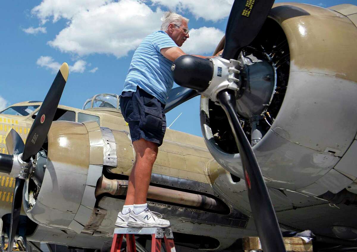 FILE - In this July 1, 2019 photo, Ernest "Mac" McCauley, a veteran pilot who volunteers with the Collings Foundation, works on one of the nine-cylinder radial engines on a B-17 Flying Fortress bomber on display at the Spokane International Airport in Spokane, Wash. McCauley, 75, of Long Beach, Calif., and his co-pilot were among seven people killed when the bomber crashed and burned Wednesday, Oct. 2, 2019, at Bradley International Airport in Windsor Locks, Conn.