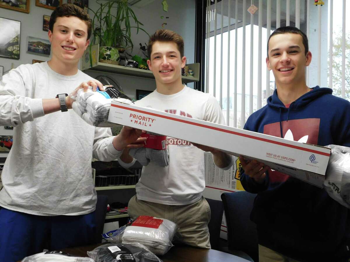 From left, Jack Savarese, Jake Zeyher and Connor Burke prepare to mail a package of socks for Wilton High School's Socks for Soldiers campaign.