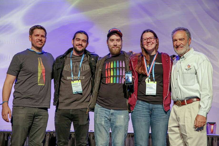   Founder of the Great American Beer Festival Charlie Papazian (R) poses with employees of the Barebottle Brewing Company at the Great American Beer Festival on Saturday, October 5, 2019. Photo: Barebottle Brewing Company 