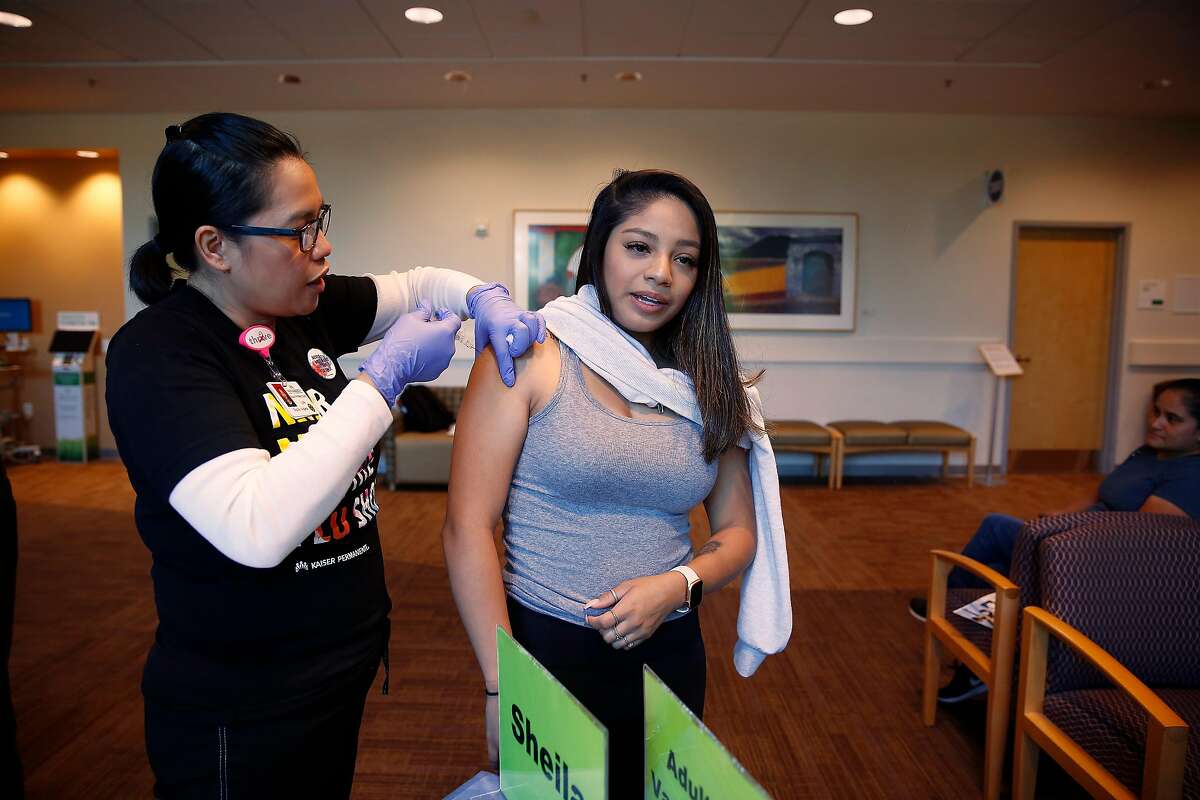Rubi Hernandez (right) of Sunnyvale, gets a flu shot at the Kaiser Permanente Santa Clara flu clinic from Shelia Aldana (left), flu clinic LVN, on Thursday, October 3, 2019 in Santa Clara, Calif.