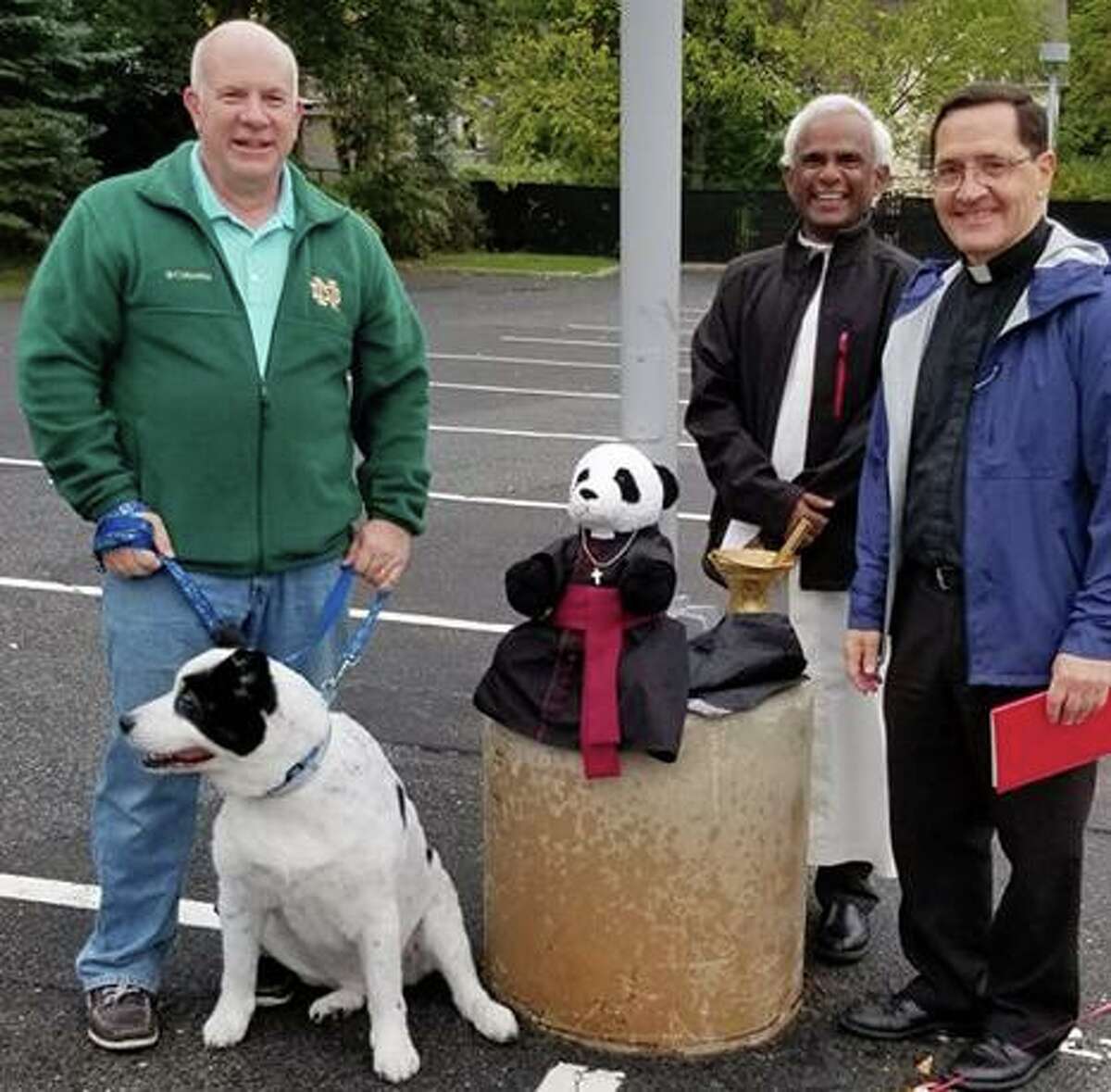 A St. Mary parishioner with his dog, left, stands with Monsignor Kevin Royal and Fr. Lourduraj at the church’s Blessing of the Animals ceremony on Sunday, Oct. 6.