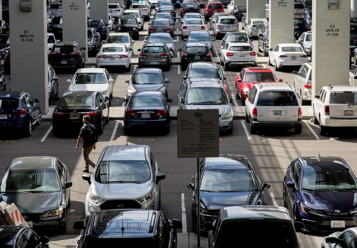 A man walks through rows of parked cars in the lots at Rockridge BART Station in Oakland, Calif. Tuesday, Oct. 8, 2019. BART is considering increasing its parking fees.