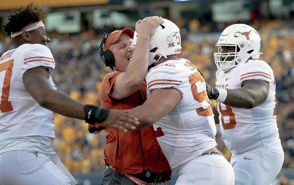 Texas lineman Samuel Cosmi (52) celebrates a touchdown with offensive line coach Herb Hand, center left, during an NCAA football game against West Virginia, Saturday, Oct. 5, 2019, in Morgantown, W. Va. (Nick Wagner/Austin American-Statesman via AP)