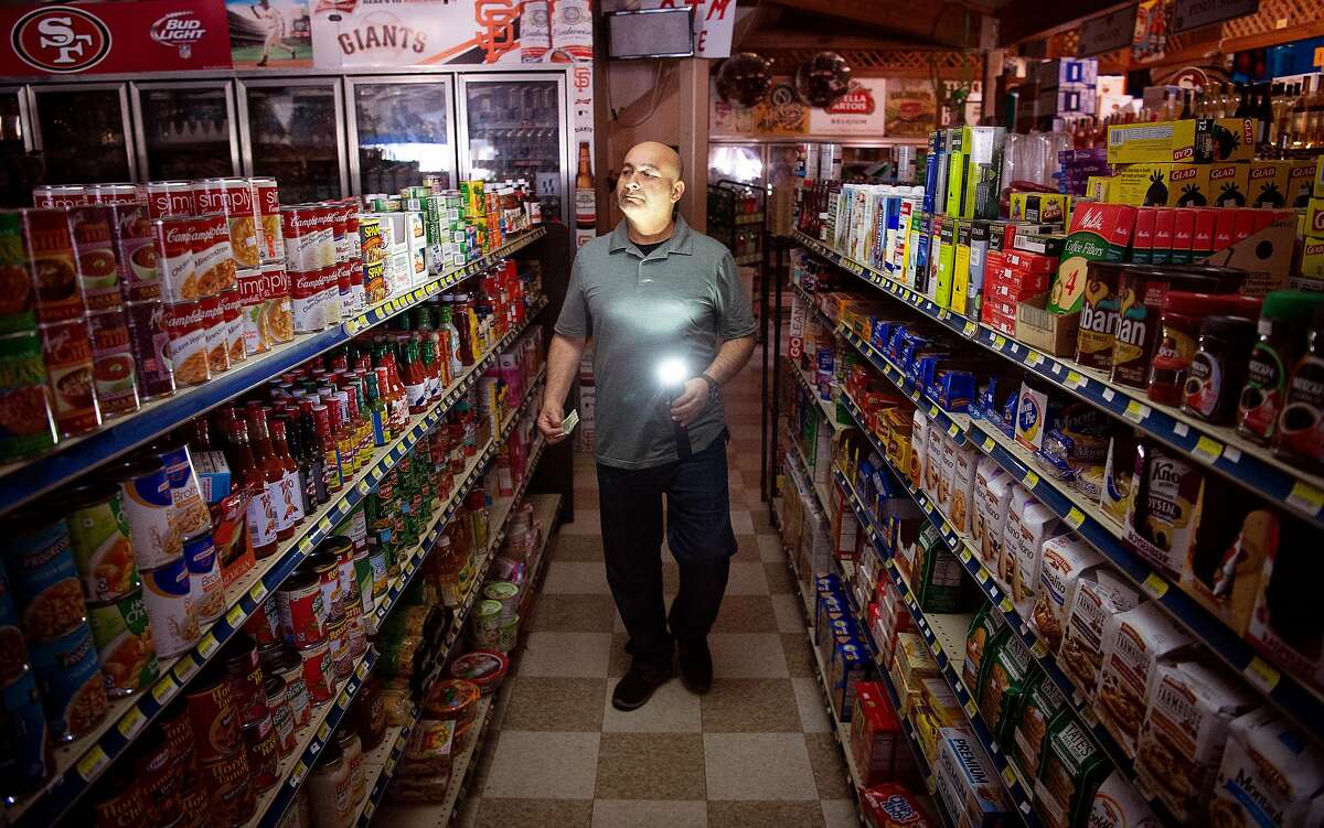 Bait Shop Market owner Akber Jiwani surveys his store with a flashlight during a state-wide blackout done as a preventative measure to combat wildfires in Sausalito on Wednesday, Oct. 09, 2019. Jiwani says he expects to lose nearly $5,000 worth of products like ice cream and other perishables during the black out.