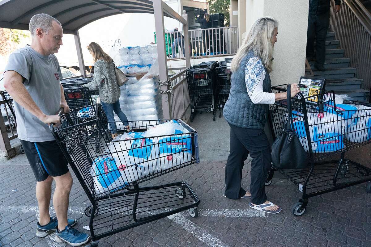 Sam Hopkin and Cindy Krystoff take ice from a pallet just delivered at a grocery store in Montclair Village on Wednesday, Oct. 9, 2019 in Oakland, Calif.