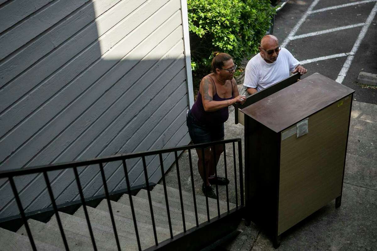 Mary Ann Stacey and Santos Galindo examine a dresser retrieved from her former apartment building before the burned structure was demolished at Villa Rodriguez Apartments on Wednesday. The crew recovered some undamaged furniture from her apartment, including the dresser and a table set that she had just purchased.