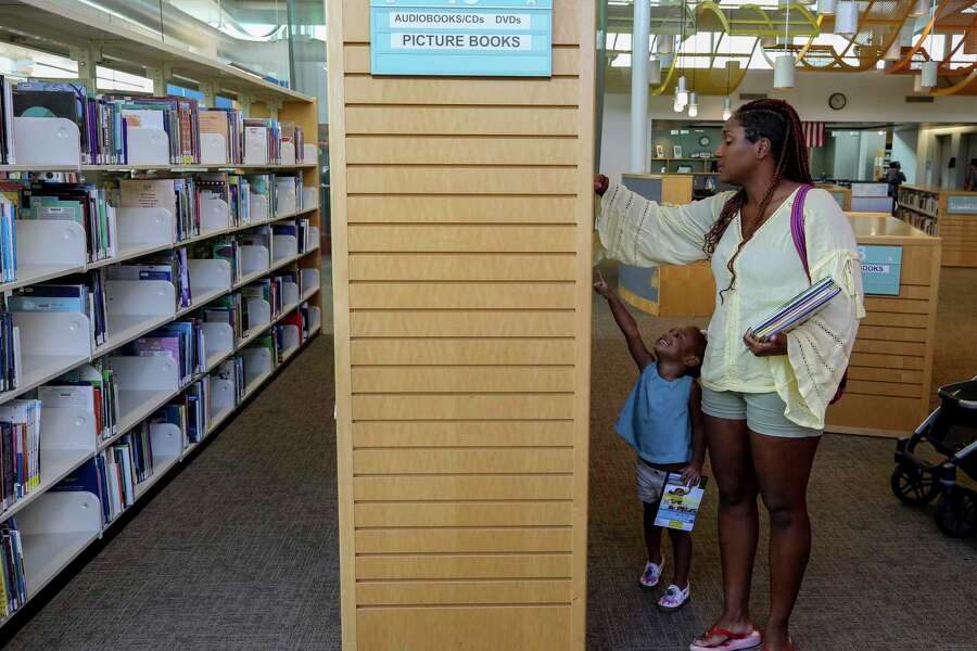 Challis Cross, right, and her three-year-old daughter Carlee look for a movie to checkout at the McGovern-Stella Link Library Tuesday, Oct. 1, 2019, in Houston. Two years ago, this library was one of 12 library branches in Houston and Harris County to close due to water damage from Hurricane Harvey.