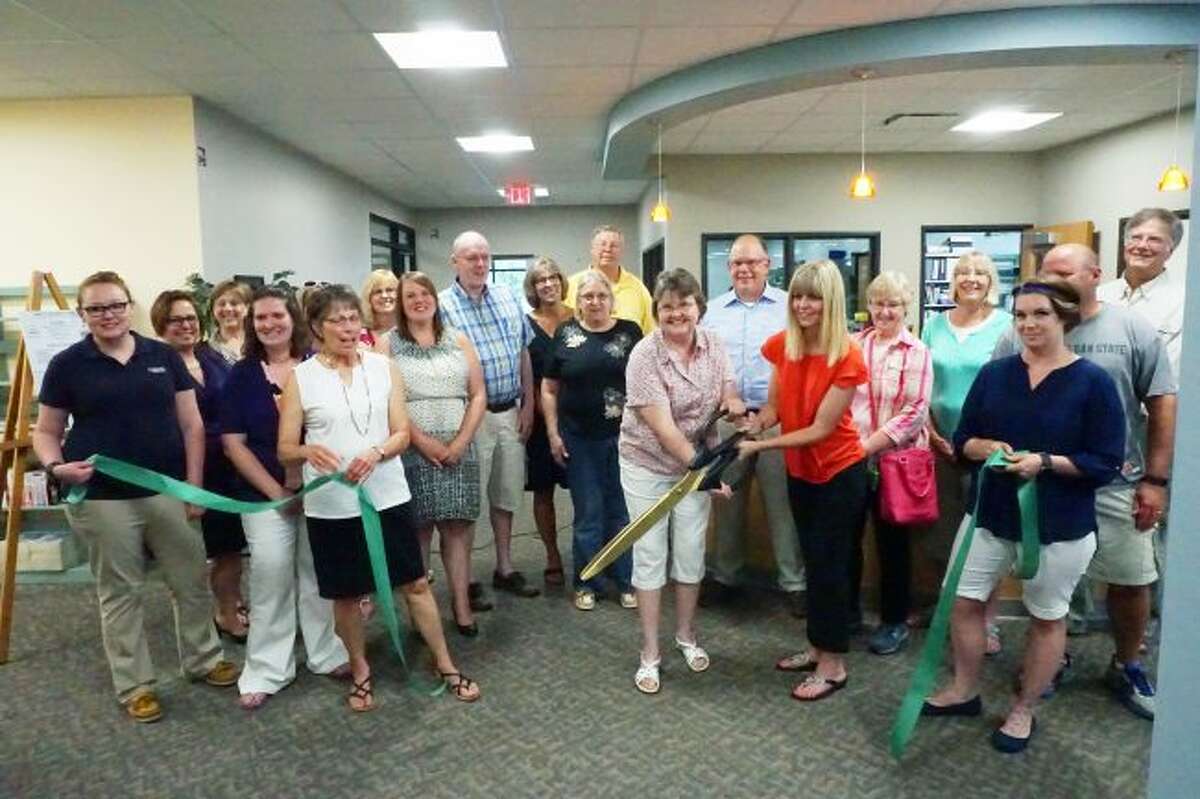 RIBBON CUTTING: Christine Cox, president of the Reed City Area Public Library board, and Heather Symon Bassett, Library Director at the Reed City Public Library, cut the ribbon to officially open the new library location on South Chestnut Street in Reed City.