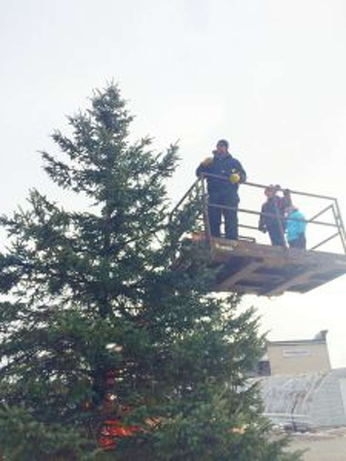 With a lift provided by Gerber Construction, Trinity’s men’s groups members Aaron Keup and Doug Emington help string the lights on the tree.