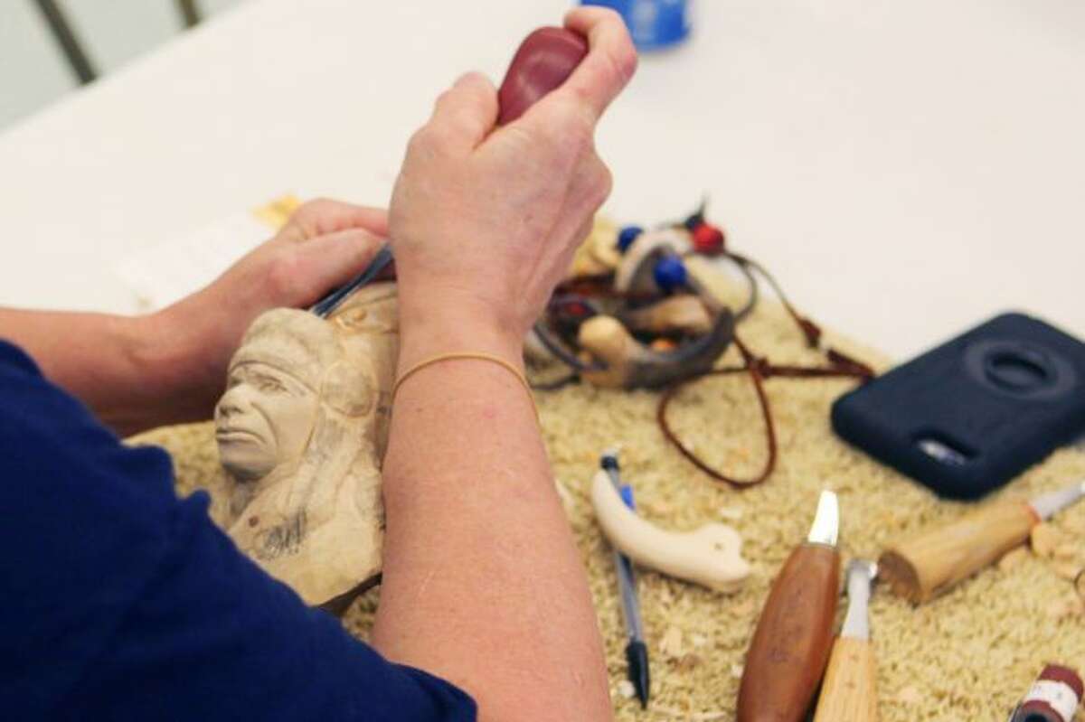 DELICATE WORK: Woodcarver Barb Reibel carefully shapes one of her projects, pulling the bust of a Native American from a block of wood.