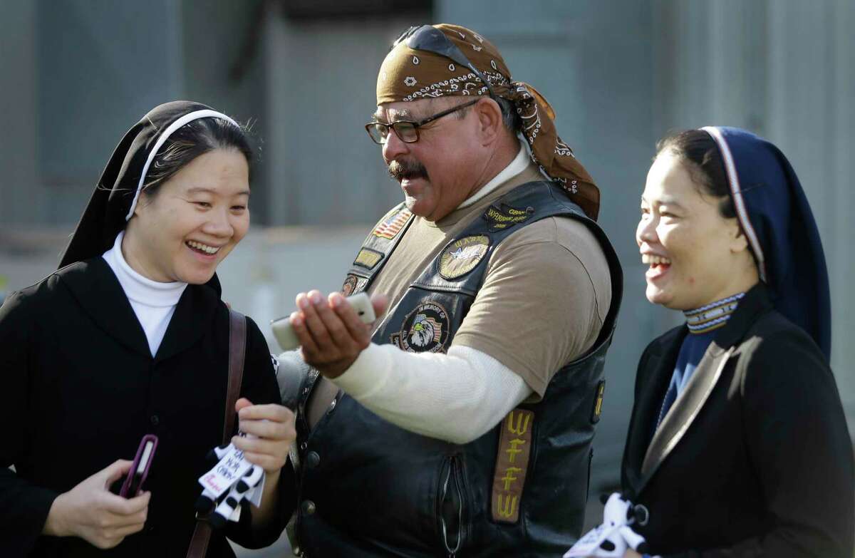 Sister Mary Oanh Ta, left, and Sister Robert Maria Trang, right, laugh as they look at cell phone photos of themselves posing on motorcycles taken by Henry Beretta, center, a member of Warriors Bikers for Christ Motorcycle Ministry, during the 11th Annual Nun Run at St. Austin Center, 2002 S. Wayside Drive, Saturday, Oct. 17, 2015, in Houston. The 40 mile ride to San Leon benefits the CHRISTUS Foundation for HealthCare school-based clinics, which provide healthcare to children on campus in 17 low-income neighborhood schools. ( Melissa Phillip / Houston Chronicle )