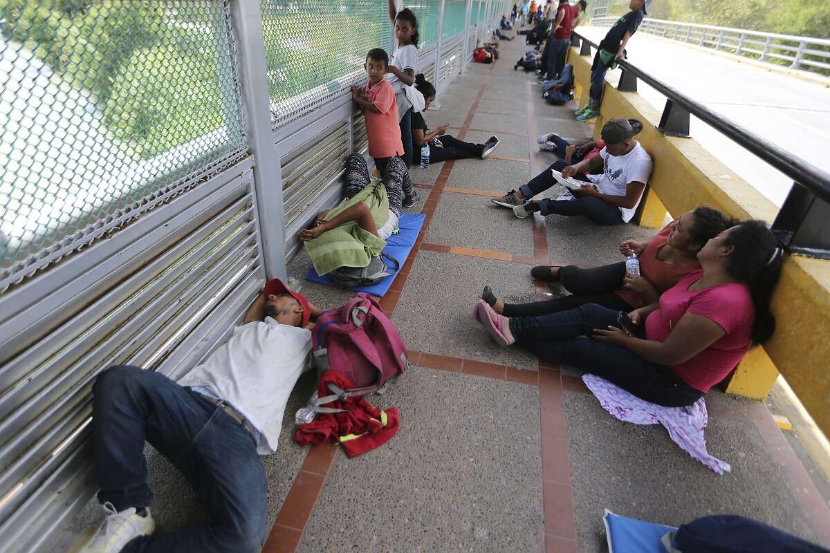 Migrants sleep on the ground after camping out on the Gateway International Bridge that connects downtown Matamoros, Mexico with Brownsville, Thursday, Oct. 10, 2019. Migrants wanting to request asylum camped out on the international bridge leading from Mexico into Brownsville, Texas, causing a closure of the span. (AP Photo/Fernando Llano)