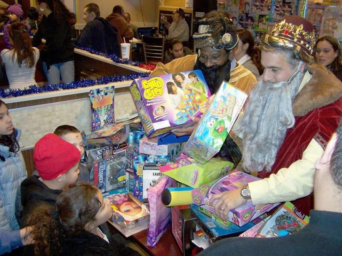 Photo by Michael Walsh - WEST HAVEN — The three kings - portrayed by, from left, New Haven Superintendent of Schools Reginald Mayo, West Haven Mayor John M. Picard and New Haven Alderman Jorge Perez, D-5, not pictured - hand out toys to four youngsters at the annual Three Kings Day celebration Jan. 6 at McDonald’s on Campbell Avenue.