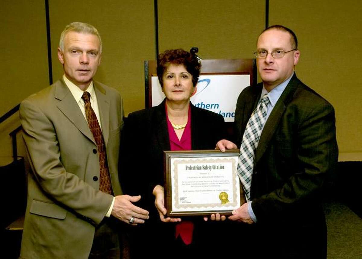 Photo by Christian Abraham - Here, Orange Assistant Police Chief Edward Koether, left; and Orange Police Chief Robert Gagne, right, receive a Public Safety Award of Excellence from AAA’s Public Affairs Manager Fran Mayko on behalf of the town that went 1 year without a pedestrian traffic fatality.