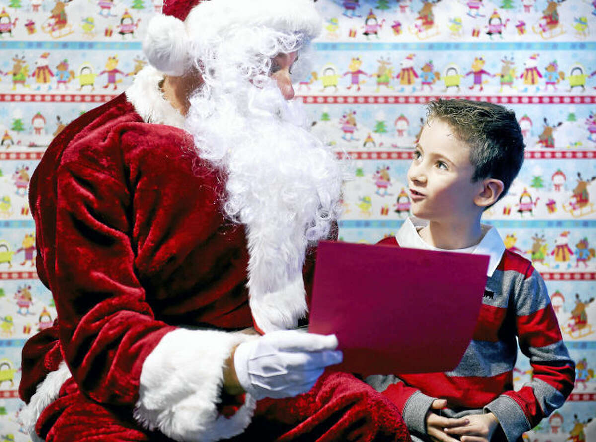 Santa Claus looks over the wish-list from Aiden Krynski, 6, of Monroe before giving him a gift at the ASD Fitness Center in Orange.
