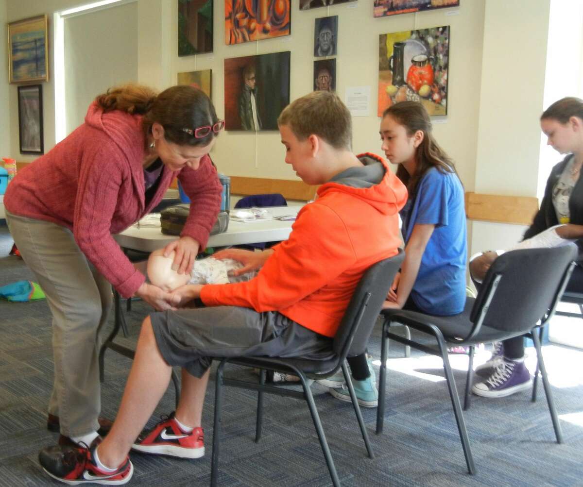 SUBMITTED PHOTO Red Cross instructor Anna Maria Mauhs shows students the proper hold for choking response at Youth Services’ babysitter training.
