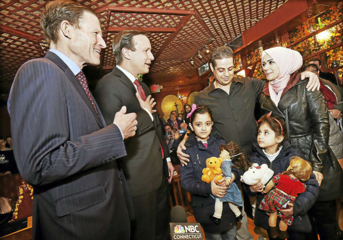 From left, U.S. Sen. Richard Blumenthal and Sen. Chris Murphy welcome Syrian refugees Fadi Kassar, his wife, Razan Ghandour, and their two daughters, Hanan Kassar, 8, and Layan Kassar, 5, at the Olive Tree Mediterranean Deli in Milford.