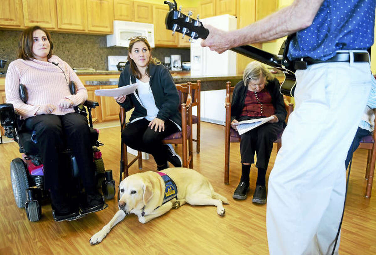 Alex Bode, 26, of North Branford, left, an intern at the Whitney Center memory support group in Hamden, observes a sing-along with Whitney Center clients earlier this month. Second from left is Bode’s personal companion assistant, Lauren Stalzer, and her service dog, Rochelle.