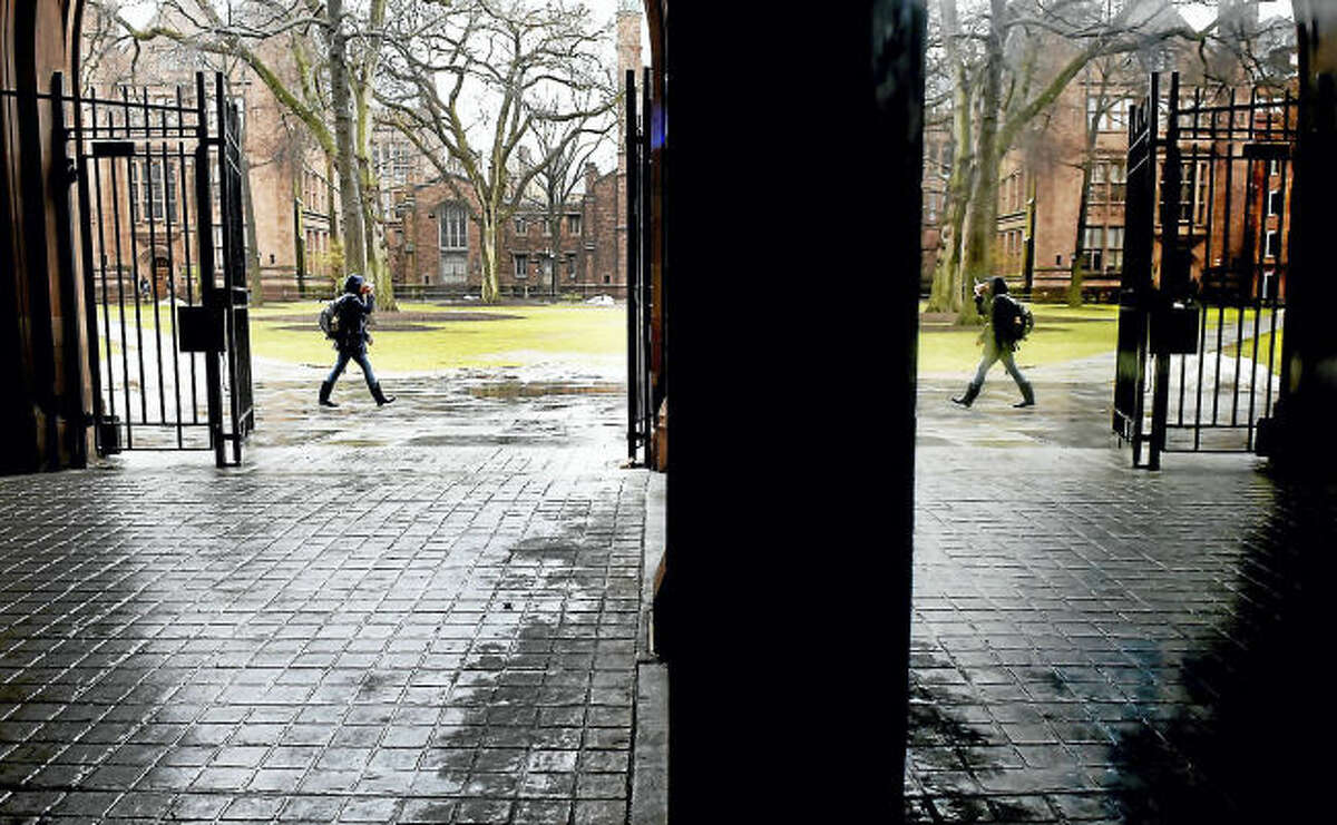 A passerby on the Yale University’s Old Campus is mirrored in a reflection on a display case inside Phelps Gate.