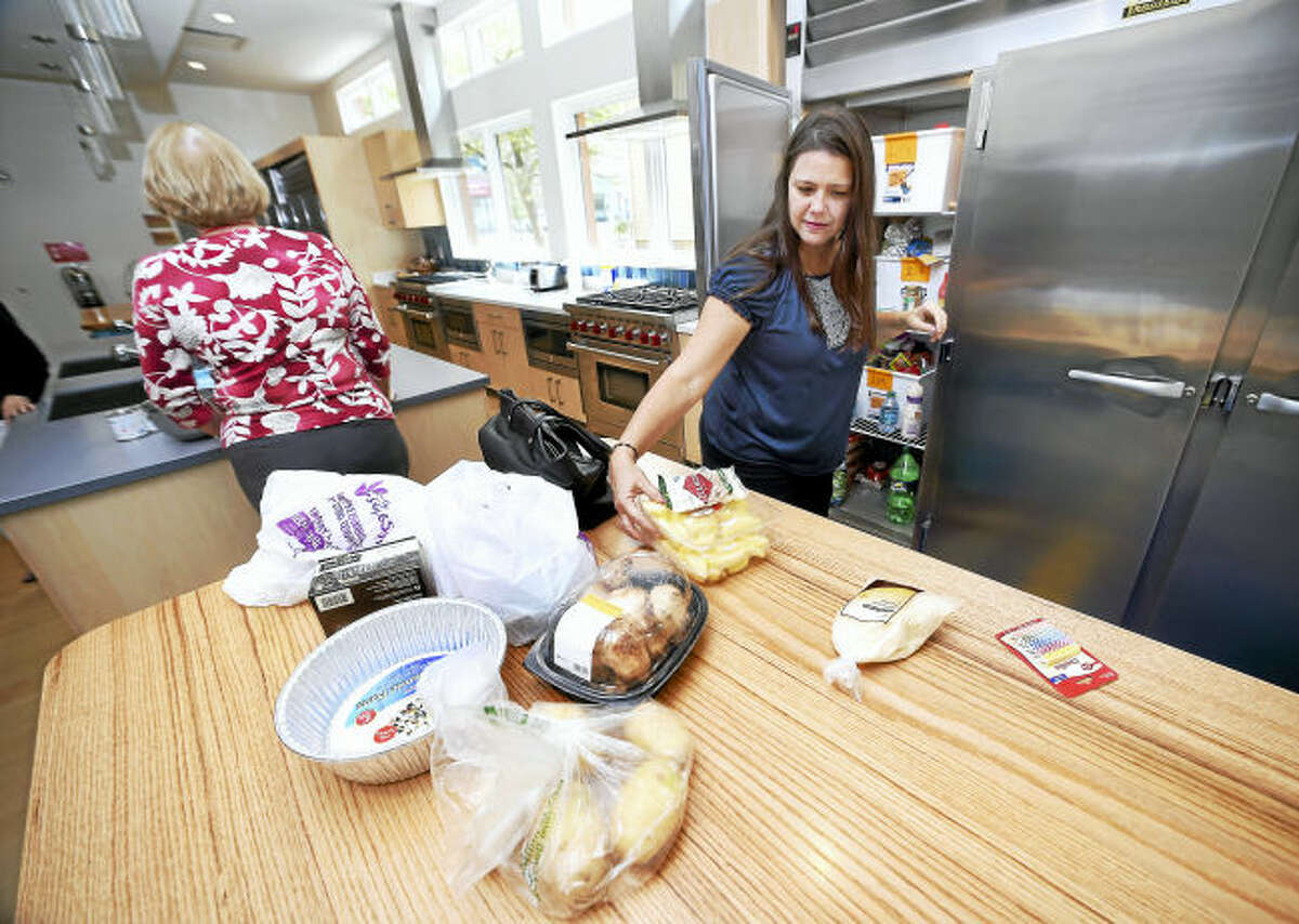 Claudia Candido of Venezuela puts away groceries in the kitchen of the new Ronald McDonald House on Howard Ave. across the street from Yale New Haven Children's Hospital in New Haven on 8/4/2017. At left is her mother, Maria Balduini. Arnold Gold / Hearst Connecticut Media