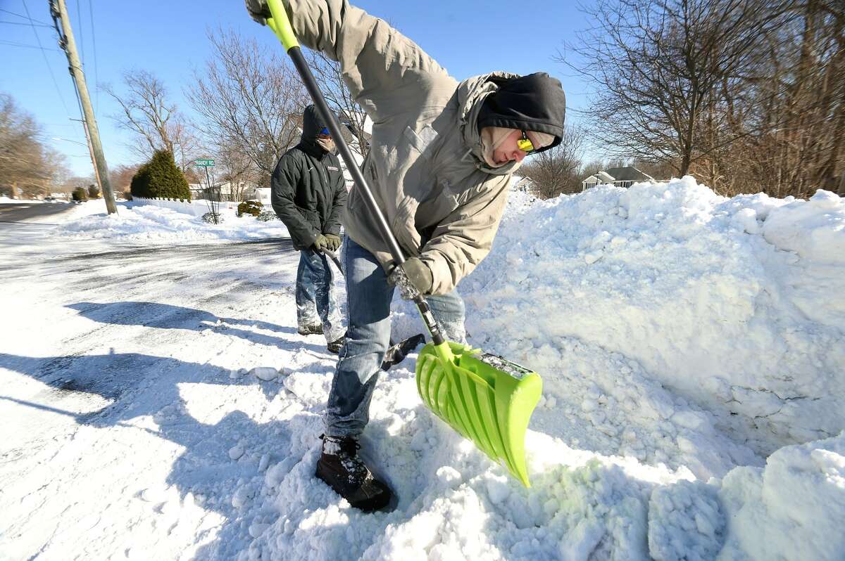 Isaac Bailey (left) and his brother, Stephen, shovel snow on a walkway at Calvary Alliance Church on Orange Ave. in Milford on Jan. 5.