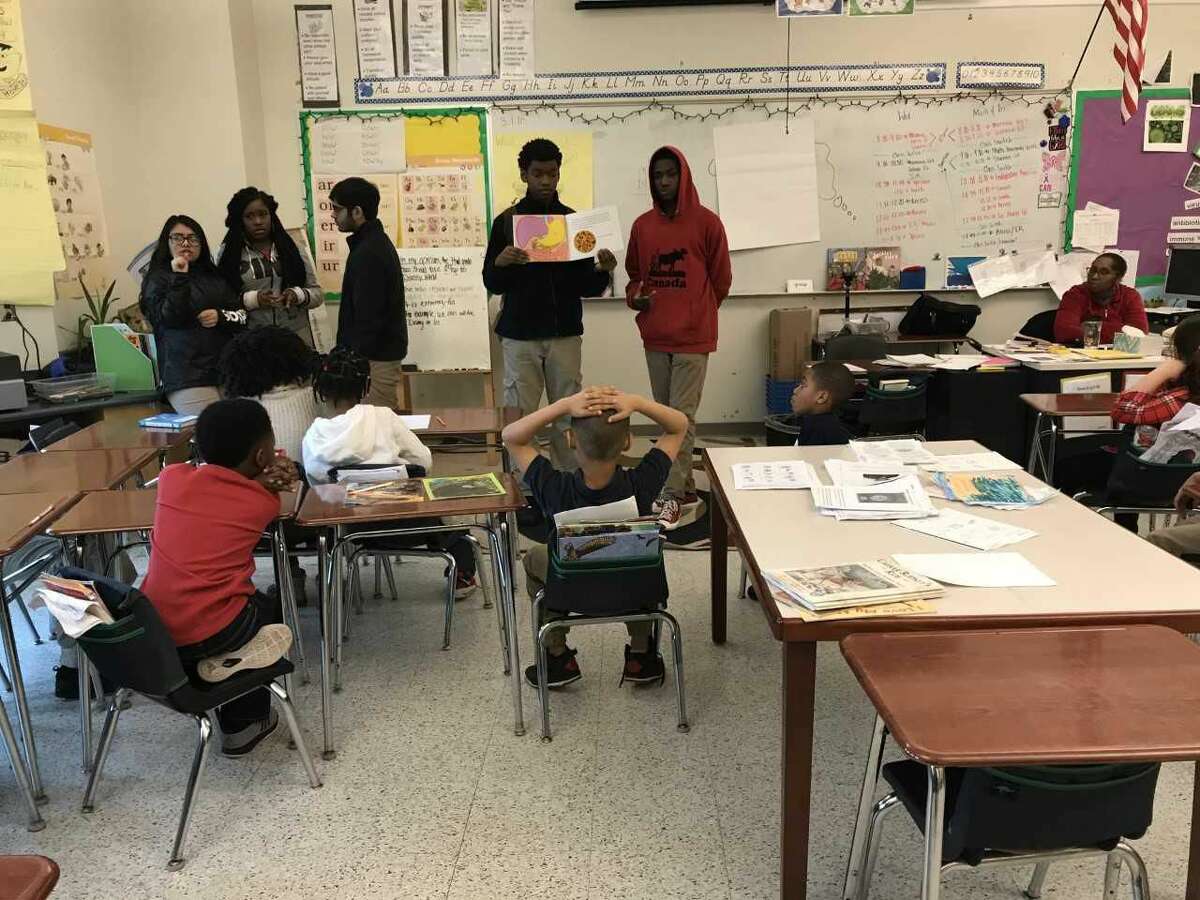 Creed High School sophomores Ssanyu Rogers and Jamar Crawford show Celentano third-graders a diagram of the human digestive system.