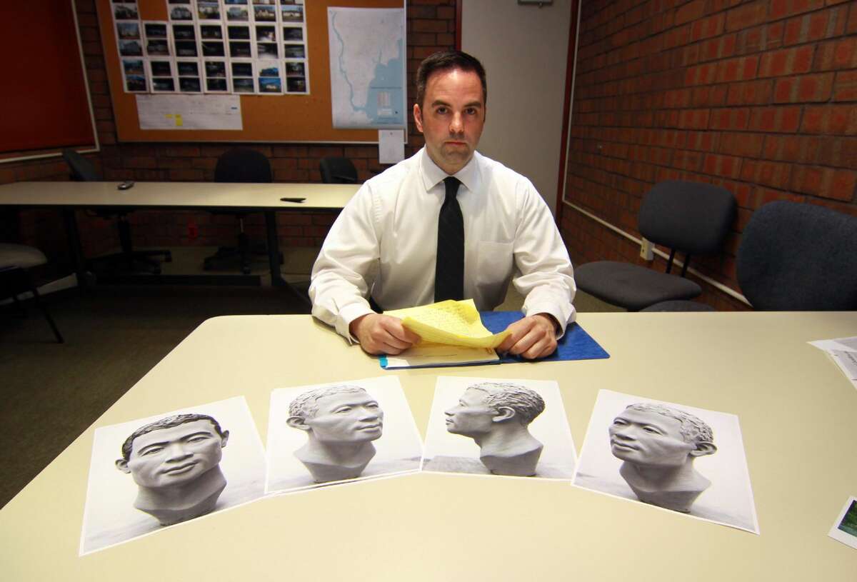 Milford Police Department's Detective Mitchell Warwick, who is responsible for two cold cases, poses at police headquarters in Milford. The photos in front of Det. Warwick depict the reconstructed face made from a skull.