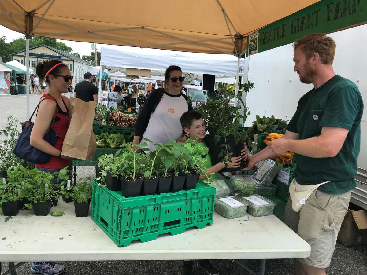 Tony Fischer, owner of Gentle Giant Farm, with customers at the farmers market.