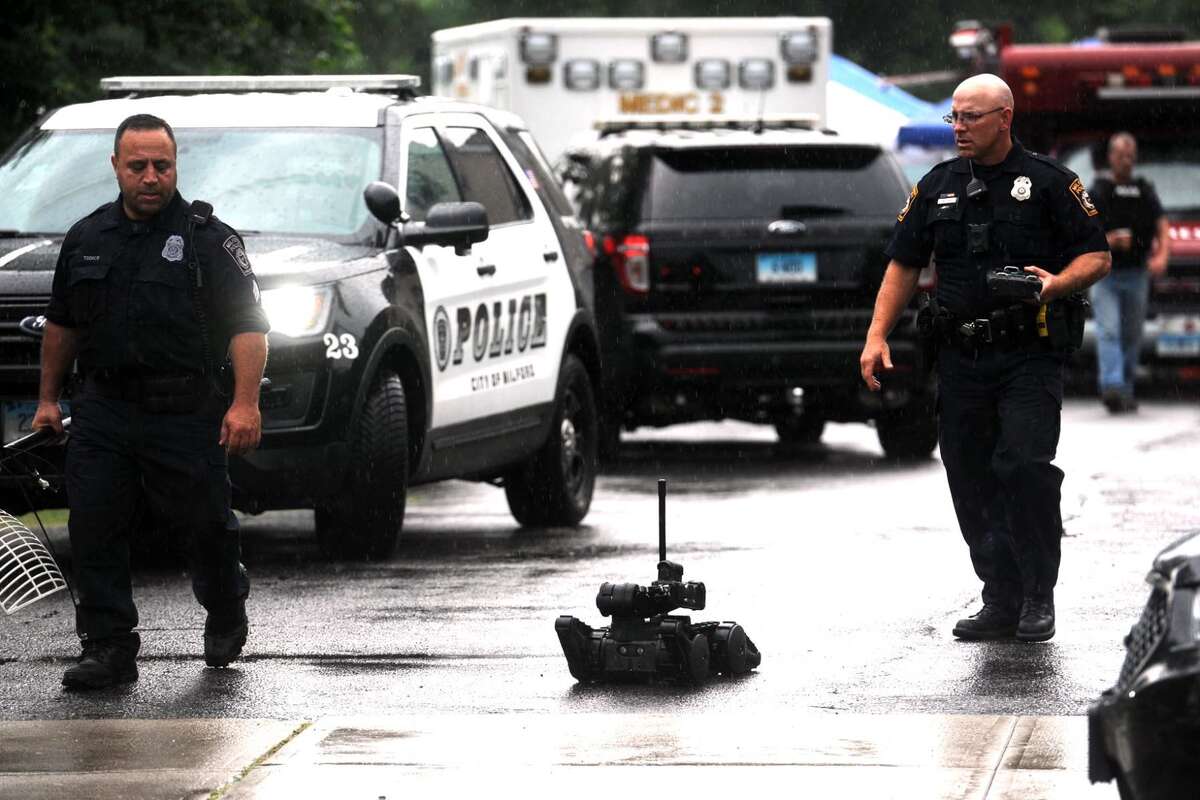 Milford Police officers leave the scene with a robot after a man was taken into custody after barricading himself inside a residence in the Beaver Brook Gardens condominiums in Milford Friday morning. After a lengthy standoff with police, the man finally gave himself up without incident.