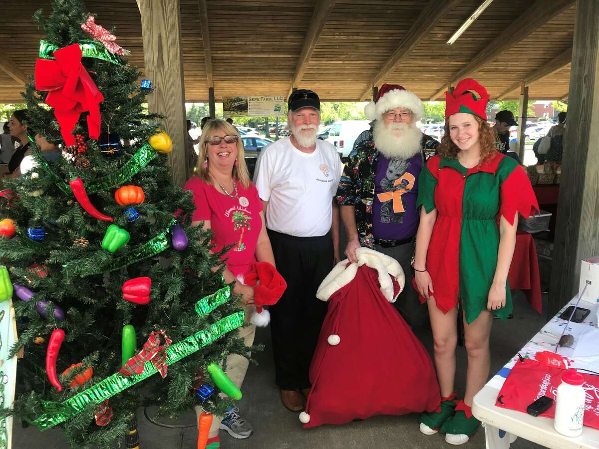 Walnut Beach Farmers Market celebrates Christmas in July with Market Master Meta Carter, Walnut Beach Arts and Business Association President Gary Dangle, Santa Claus (Rick George) and Elf Anna Downs.