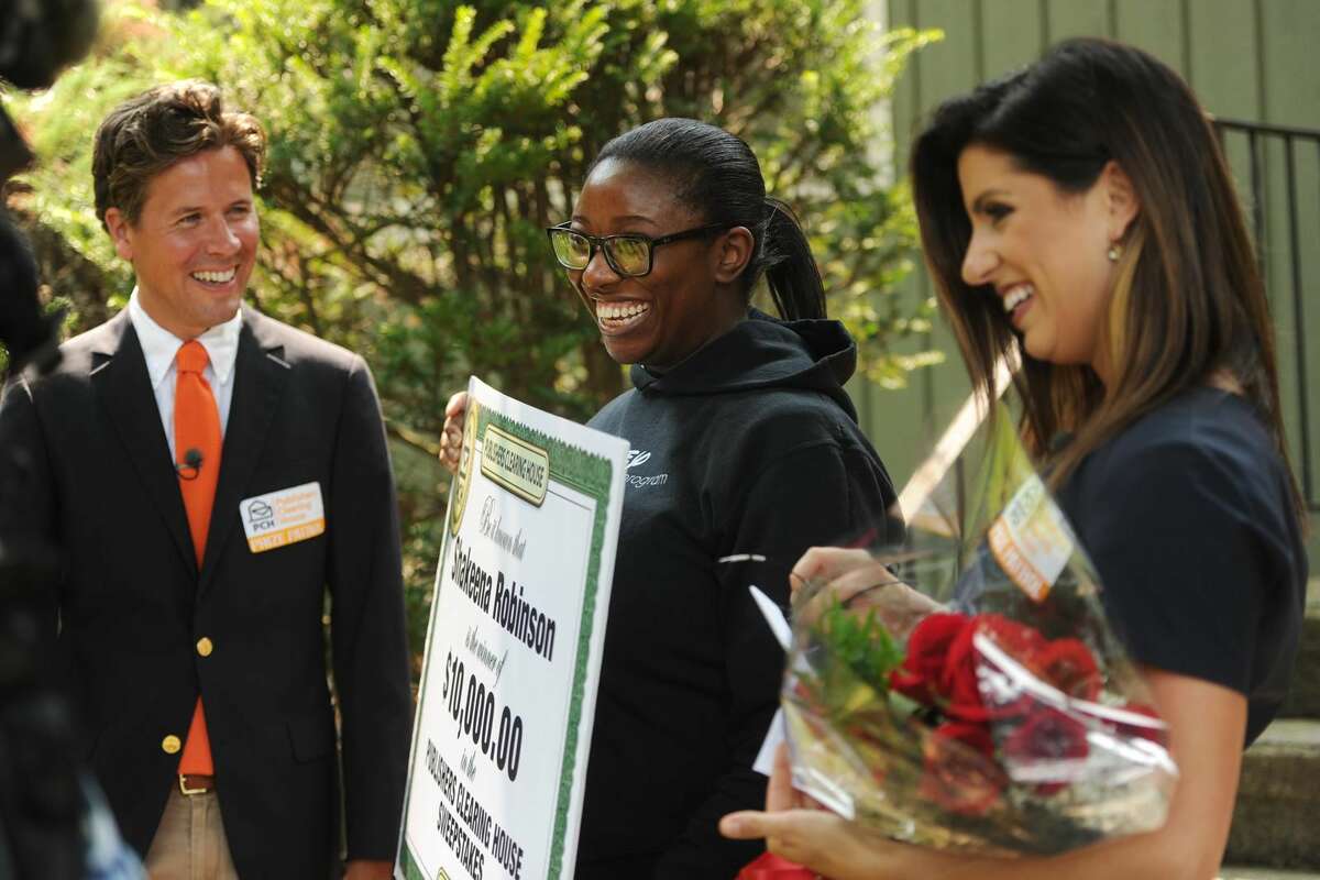 Shakeena Robinson, center, of Milford, is surprised by Publishers Clearing House Prize Patrol members Howie Guja, left, and Danielle Lam with a ten thousand dollar prize at her home.